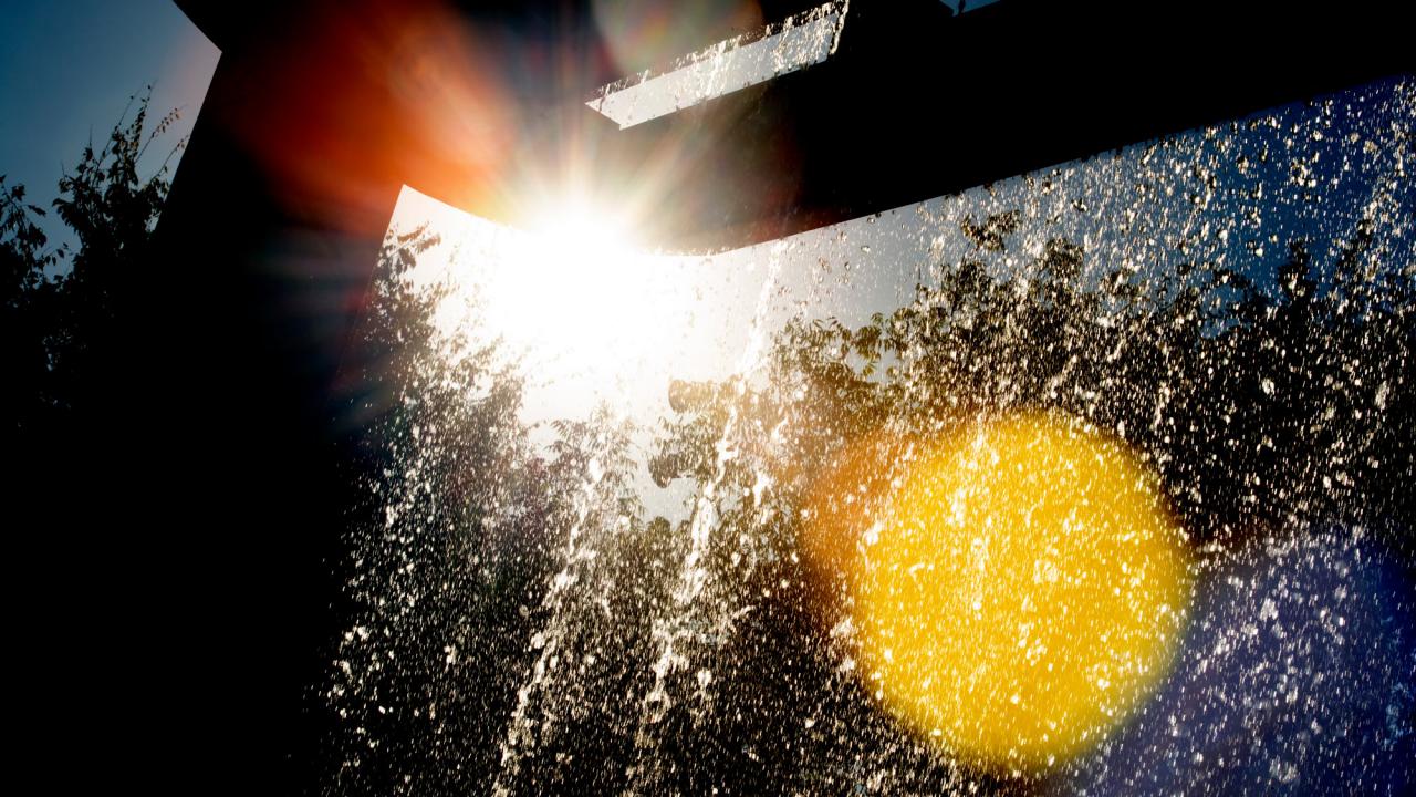 Sun shines through Morris Fountain's flowinjg water.