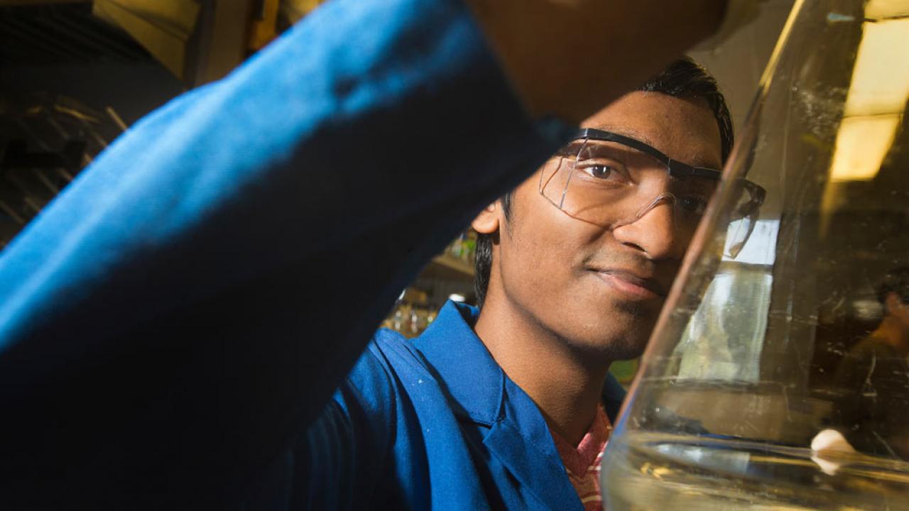 A male student holds up the contents of a lab flask