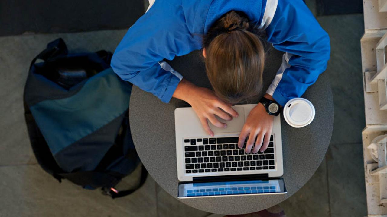 An overhead view of a student working on a laptop