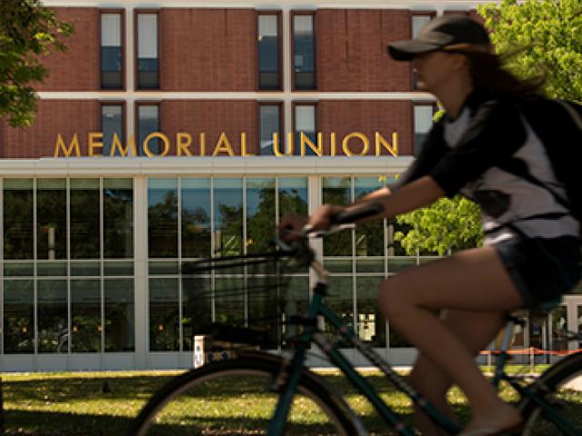 student rides her bike near uc davis memorial union
