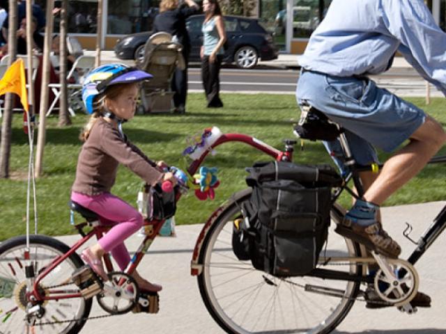 A parent and their child riding a tandem bicycle