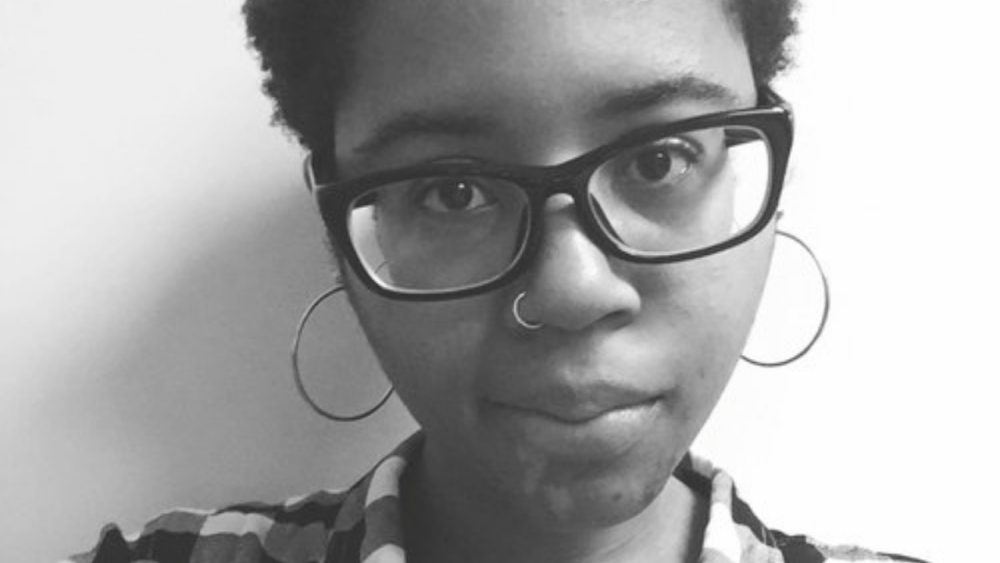 Black woman, with glasses, in moodly black and white photo