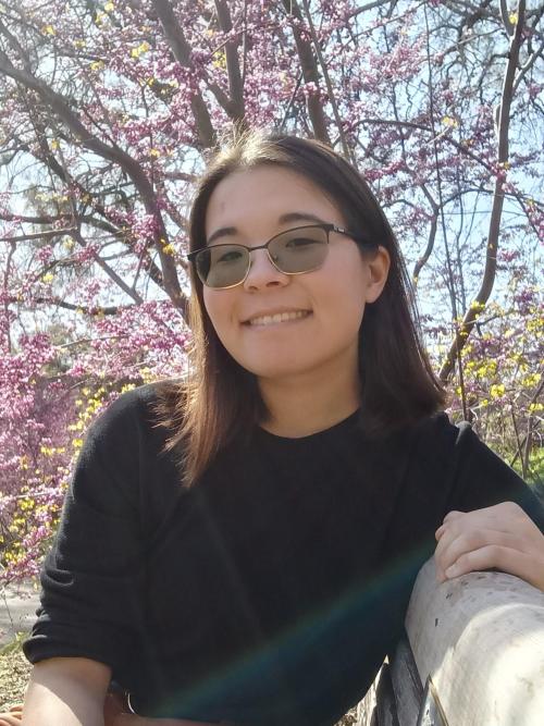 A selfie of Franchesca Christie outside in front of a pink floral tree.