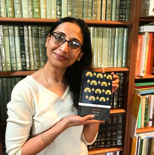 Archana Venkatesan displays prize-winning book, against backdrop of bookcase.