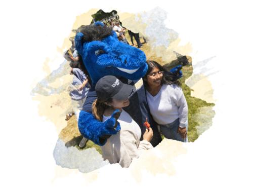Gunrock the mascot with his arms around two students at an outdoor event