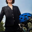 Sydney Vergis in suit standing with bicycle and helmet