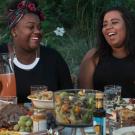 Photo of two women laughing while sharing a picnic dinner