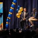 Chancellor Gary S. May at the mike with two students hosting a podcast