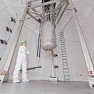 Man in white suit in a huge tank looking at a hanging dark matter detector
