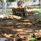 Equipment operator excavates the historic path where a concrete walkway has been removed to make way for the new Centennial Walk.