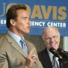 Photo: Gov. Schwarzenegger speaking at microphone with man looking on from right.