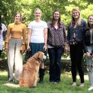 Assistant Professor Gwen Arnold, flanked by some of her students, in a line facing the camera, with Doug the Dog next to Gwen