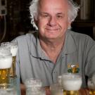 Charlie Bamforth sits behind a dozen glasses of foam-topped beer.