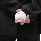 suited man holds a baseball behind him