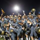 Football players celebrate and pose with the Golden Horseshoe trophy.
