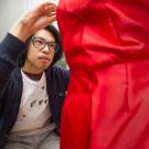 Jason Lin adjusts his red dress on a mannequin