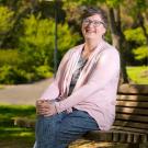 Dean Lauren Lindstrom, casually sitting on bench in the arboretum.