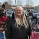 A man holding a German shepherd-mix puppy stands next to a woman in a black coat and a woman holding a large box of dog supplies