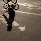 A student's shadow is seen on a bike path.