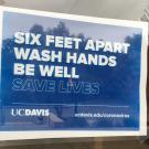 Sign on door: "Six Feet Apart. Wash Hands. Be Well. Save Lives."