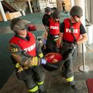 Firefighters in body armor carry a mock patient during a drill.