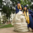 Miguelangel Turcios, left, and his sister, Christy, pose in graduation gowns on an Egghead sculpture.