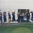 Twelve students jump up in front of a building