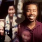 African American male student poses in front of photos of African American graduates