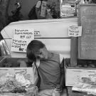 A young merchant rests his eyes at a produce stand at the Davis Farmers Market