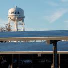 UC Davis water tower rises above carport roofs covered in solar panels on campus