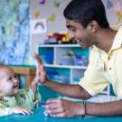 Neeraj Senthil and a toddler share a high 5 in a playroom at UC Davis Children's Hospital.
