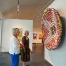 Two museum visitors look at artwork of smashed cans displayed at Gorman Museum of Native American Art