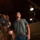 A student smiles with a horse in a barn at UC Davis. 