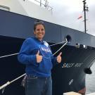 Woman in NASA sweatshirt stands in front of boat called Sally Ride