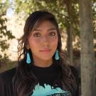 Native America woman in black shirt and blue earrings looks directly at camera for a series on climate anxiety. 