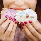 Woman's face visible from the nose down, as she eats two cupcakes