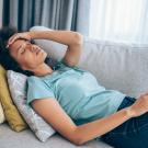 Person reclining on couch holding head as if she has a headache