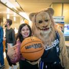 Woman holds basketball posing next to Kings mascot