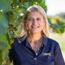 UC Davis enologist Anita Oberholster, pictured here standing next to a vineyard, and two of her colleagues from other universities are being recognized for their research on how wildfire smoke affects grapes, grapevines and wine composition.