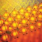 Rows of bright orange tetrahedral shapes against a red/yellow background. 