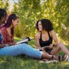 Students sit on grass to talk and study with books