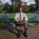 Chancellor Gary S. May, sans coat, smiling, sitting in hammock on Quad.