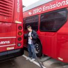 Person plugs red Unitrans bus into electric charger