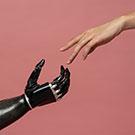 A robotic hand reaches out to another human hand.