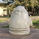 Person walks by the "Eye on Mrak" Egghead sculpture