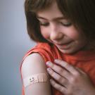 Girl stares at her vaccination Bandaid.