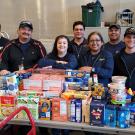 Mail Services personnel pose behind a tableful of donated food