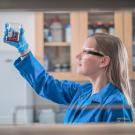 female scientist in lab with blue coat looking at water sample
