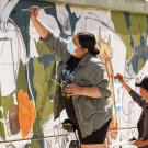 Two students paint a mural at a school