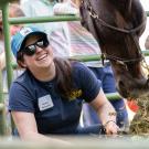 Woman squats near horse in petting zoo